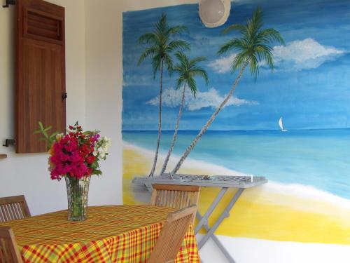 a table with a vase of flowers and palm trees at LAPALOMADESANSEs2 in Les Anses-dʼArlets