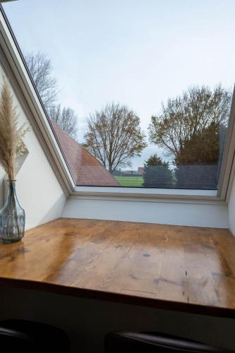 a room with a wooden table in front of a window at Appartementen De Witte Brugh in Buren