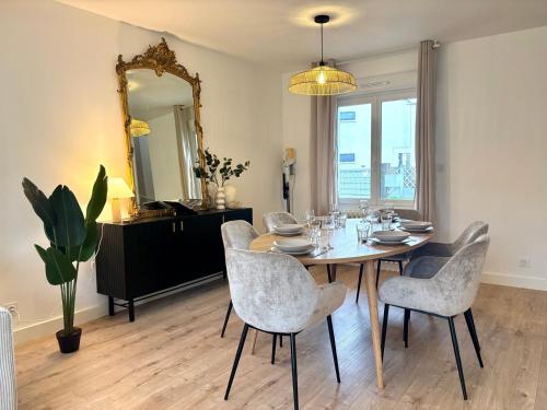 une salle à manger avec une table, des chaises et un miroir dans l'établissement Le Jouon - Magnifique Maison de Ville avec Jardin, à Rennes