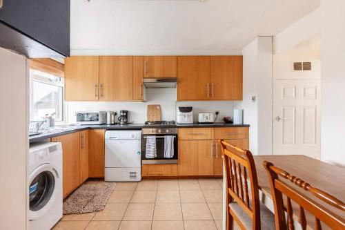 a kitchen with wooden cabinets and a table with a washer at Spacious Room by Lee Valley White Water Centre. Waltham Cross in Waltham Cross