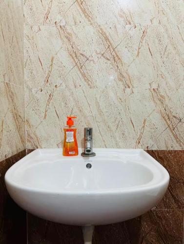 a white sink with an orange soap dispenser on it at Deluxe Rooms near Tree Park Metro station Whitefield in Bengaluru