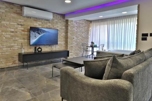 a living room with couches and a tv on a brick wall at שקיעה בים 75 - דירה מהממת עם ג'קוזי ספא ליד הים יש מקלט in Haifa