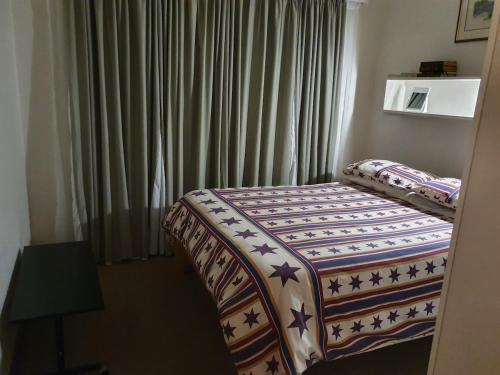 a bed in a hotel room with a window at Betty's Bay Quaint Cottage in Bettyʼs Bay