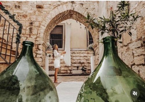 two green glass vases with a woman standing in a doorway at Blanco B&B - Group Puglia in Trani
