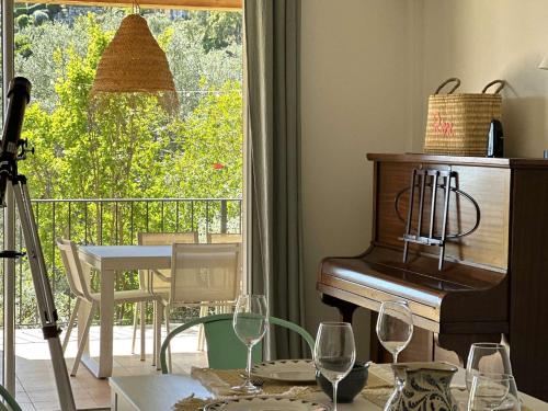Cette chambre comprend un piano et une table avec des verres à vin. dans l'établissement VILLA ELODIE climatisée pour 10 personnes avec piscine privée à La Londe les Maures, à La Londe-les-Maures