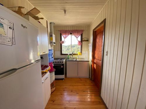 a small kitchen with a refrigerator and a sink at Cabaña en Mechaico, 10 min Ancud in Ancud