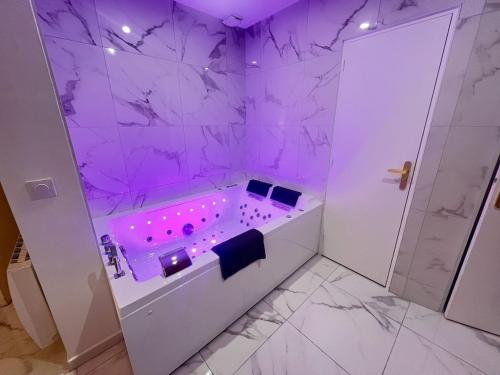d'une salle de bains pourpre avec une baignoire à éclairage violet. dans l'établissement Love Room Suite Jacuzzi, à Les Pavillons-sous-Bois