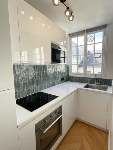- une cuisine avec des plans de travail blancs et un évier dans l'établissement Renovated Studio Centre Paris-24m, à Paris