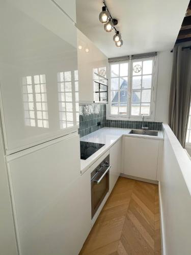 La cuisine blanche est équipée d'un évier et d'un réfrigérateur. dans l'établissement Renovated Studio Centre Paris-24m, à Paris
