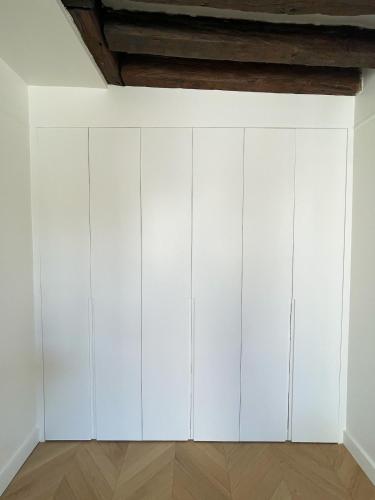 une rangée de placards blancs dans une pièce dans l'établissement Renovated Studio Centre Paris-24m, à Paris