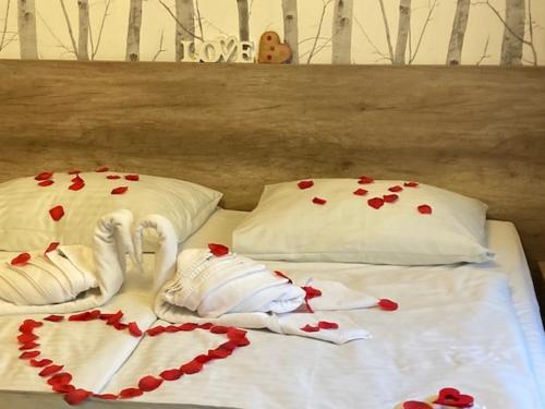 a bed with two swans and hearts on it at Erdővarázs Panzió in Lillafüred