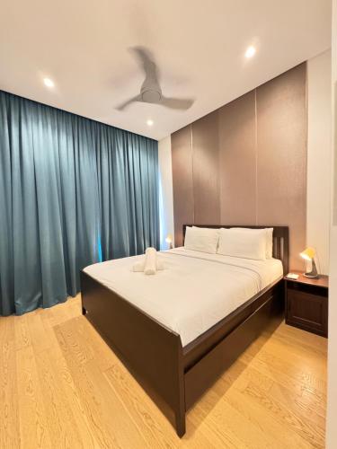 a bedroom with a large bed with blue curtains at LUCENTIA RESIDENCE By LALAPORT in Kuala Lumpur