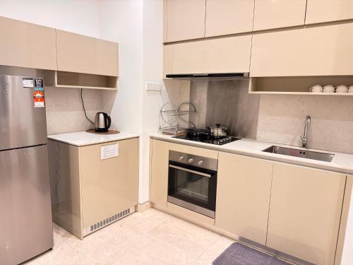 a kitchen with white cabinets and a stainless steel refrigerator at LUCENTIA RESIDENCE By LALAPORT in Kuala Lumpur