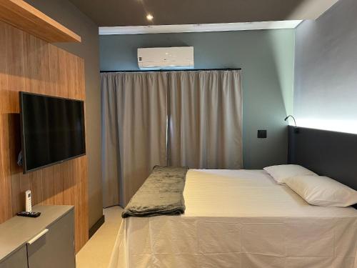 a bedroom with a bed and a flat screen tv at Globo Lar Studios in Limeira