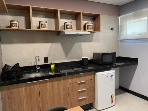 a kitchen with a sink and a microwave at Globo Lar Studios in Limeira