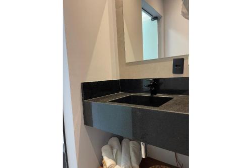 a bathroom with a sink and a mirror at Globo Lar Studios in Limeira