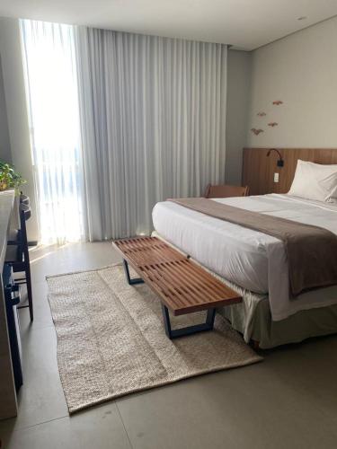 a bedroom with a large bed and a wooden bench at Zank by Toque Hotel in Salvador