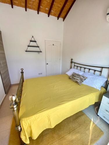 a bedroom with a bed with a yellow bedspread at The Bungalow Kyrenia North Cyprus in Ayios Ioannis