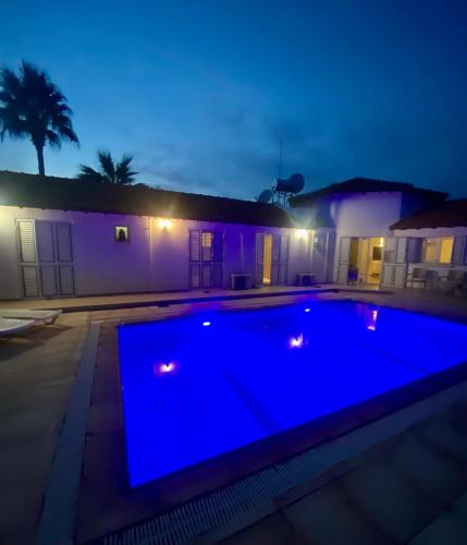 a blue swimming pool in front of a house at night at The Bungalow Kyrenia North Cyprus in Ayios Ioannis