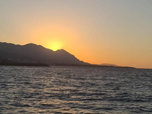 a sunset over the water with mountains in the background at The Bungalow Kyrenia North Cyprus in Ayios Ioannis