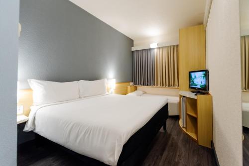a hotel room with a large bed and a tv at ibis Criciuma in Criciúma