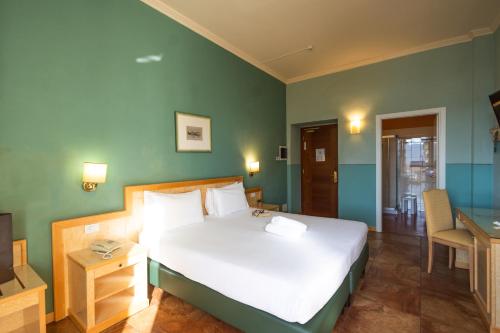 a bedroom with a large white bed and green walls at Hotel Belvedere San Gottardo by LVG Hotel Collection in Verbania