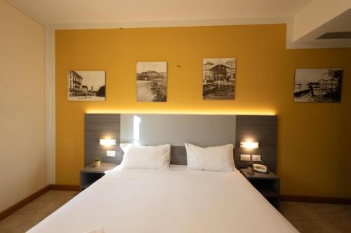 a bedroom with a large white bed and some pictures on the wall at Hotel Belvedere San Gottardo by LVG Hotel Collection in Verbania