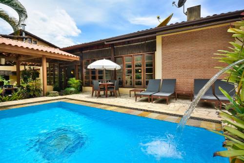 a swimming pool with a table and an umbrella at Pousada Estalagem Casa Grande in Ubatuba