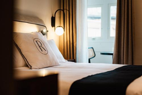 a hotel room with a bed with a pillow with the letter r at Royale Sainte Hélène Boutique Hotel in Birkirkara
