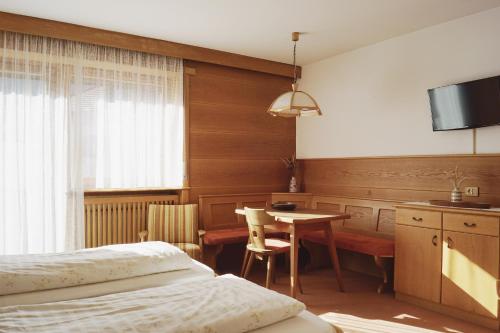 a bedroom with a bed and a table and a tv at Belpra in Ortisei