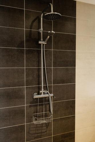 - une douche avec un pommeau sur un mur carrelé dans l'établissement Maison comprenant deux gîtes à louer, ensemble ou indépendamment, capacité de 4 à 19 personnes Idéalement placé pour visiter le Mont-Saint-Michel, Saint-Malo et les alentours, à Baguer-Pican