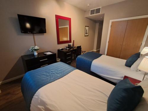 a hotel room with two beds and a television at The Royal Hotel Cardiff in Cardiff