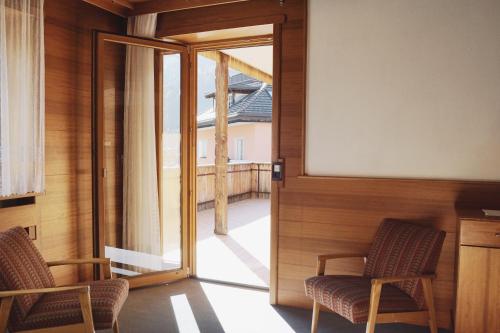 a room with two chairs and a sliding glass door at Belpra in Ortisei