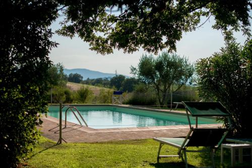 a swimming pool in a yard with a chair at Agriturismo Palazzo Val Del Sasso in Villastrada