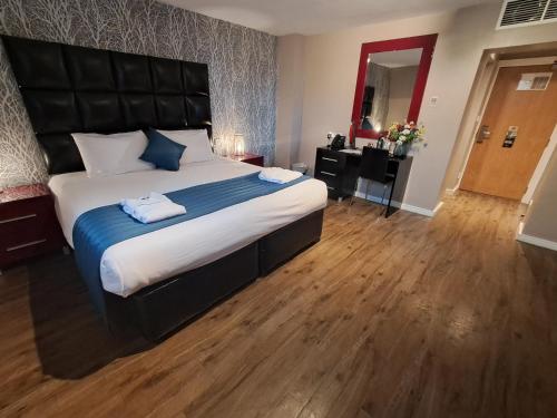 a bedroom with a large bed with a black headboard at The Royal Hotel Cardiff in Cardiff