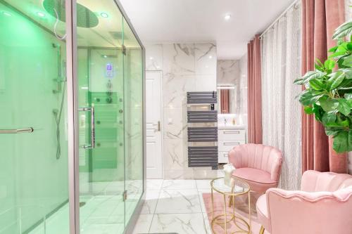 La salle de bains est pourvue d'une douche en verre et d'une chaise rose. dans l'établissement Suite Hammam Love Luxe paisible, à Les Pavillons-sous-Bois