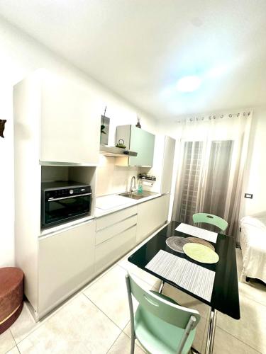 a white kitchen with a table and chairs in a room at Alloggio by the sea in Focene