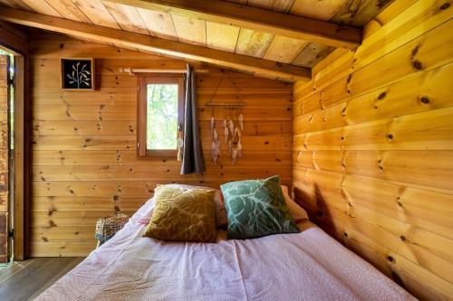 une chambre avec un lit dans une cabane en rondins dans l'établissement Cabane Perchée avec Jacuzzi, au Coeur du Luberon, à Oppède
