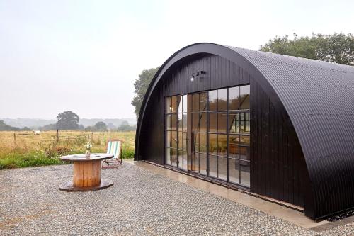 a black building with a table in front of it at Converted Nissen Barn on beautiful farm in Braintree