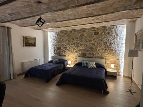 a bedroom with two beds and a stone wall at Dream House Castellana in Castellana Sicula