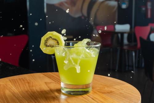 a drink with a kiwi slice in a glass on a table at ibis Criciuma in Criciúma