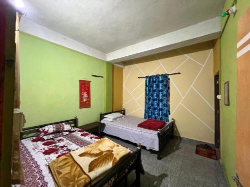 two beds in a room with green walls at Rise And Shine Homestay in Mirik