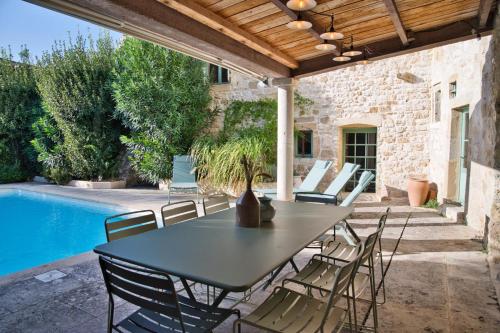 un patio avec une table et des chaises à côté d'une piscine dans l'établissement Mas piscine exposition sud Proche Uzès, à Collorgues