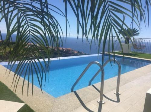 a swimming pool with a view of the ocean at Vila Da Luz Calheta in Estreito da Calheta