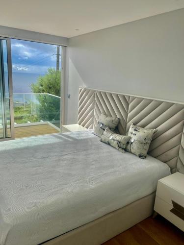 a bedroom with a large bed with a large window at Vila Da Luz Calheta in Estreito da Calheta