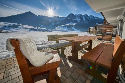 a picnic table and bench on a balcony with mountains at Hotel Garni Tirol in Walchsee