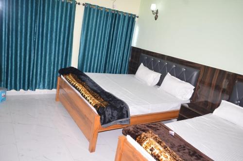 a bedroom with two beds and blue curtains at HOTEL AV Priya Rajgir in Rājgīr