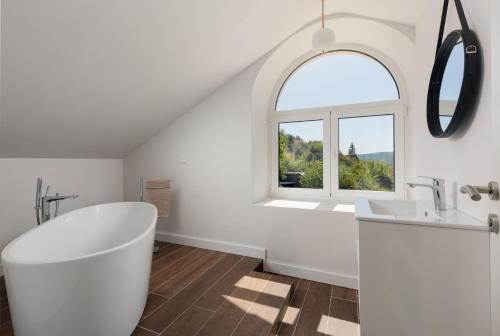 a bathroom with a white tub and a window at Villa Magic Stone in Šišići