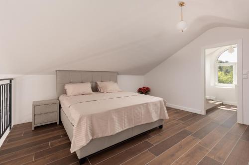 a white bedroom with a bed and a window at Villa Magic Stone in Šišići