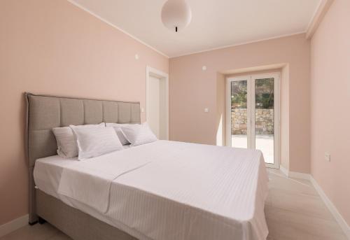Um quarto branco com uma cama grande e lençóis brancos. em Villa Magic Stone em Šišići